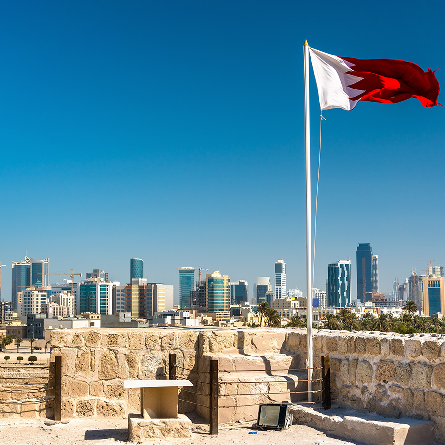 Bahrain Flag with skyline of Manama at Bahrain Fort. A UNESCO World Heritage Site in the Middle East