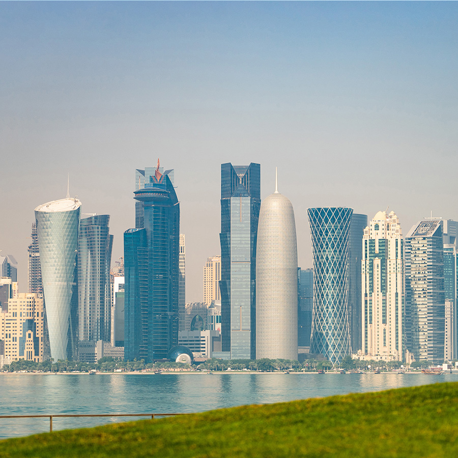 panoramic view of modern skyline of doha with green grass foreground