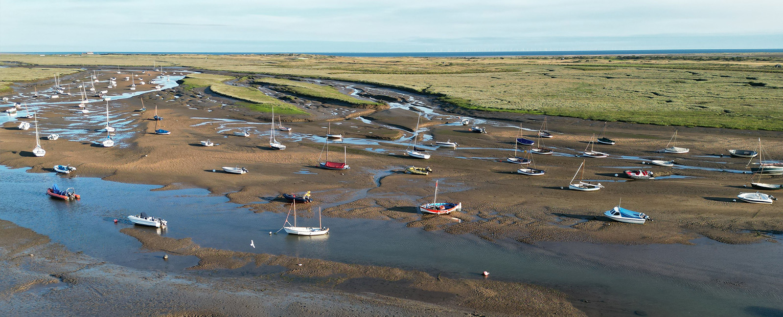 A high-angle shot of Brancaster Staithe in the morning with mudflats and low tides
