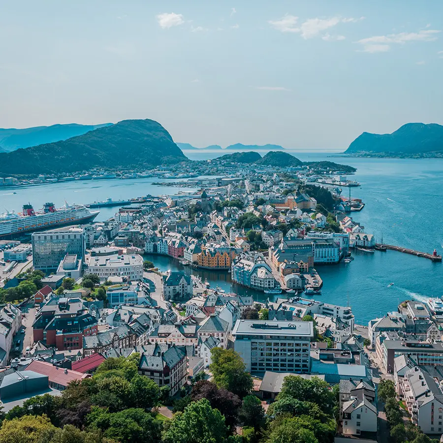 high angle shot of a lot of buildings on the seashore near high mountains in norway