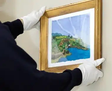 White gloved hand handling a gilt framed painting during a fine art move